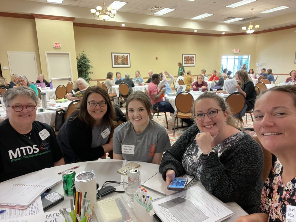 Teacher academy participants sit at a table and enjoy their learning.