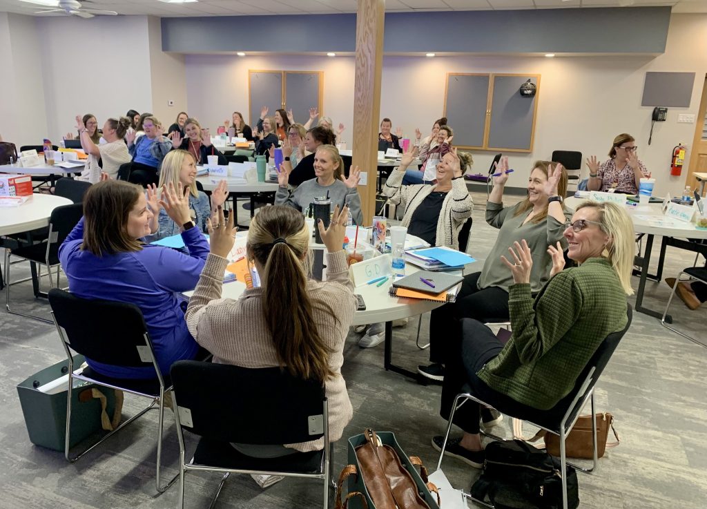A table of people holding their hands up